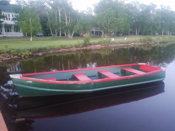 A green rowboat with red seats docked at a calm water body.