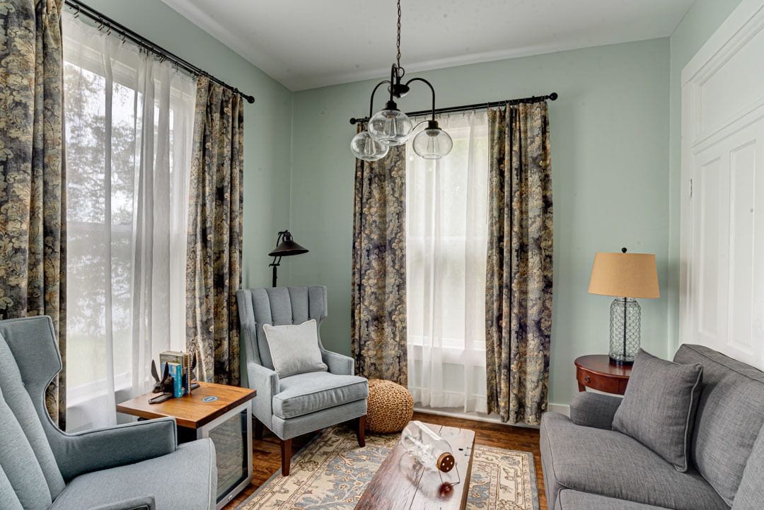 Un salon avec un canapé, un fauteuil et une petite table sur laquelle se trouve une lampe.