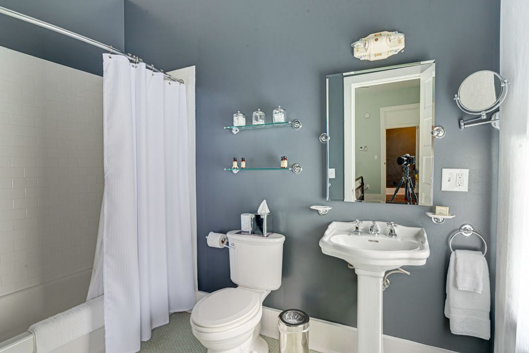 A bathroom with a white toilet, a sink, a shower with a white curtain, and a mirror.