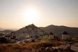 Un pueblo costero con edificios blancos, una estructura destacada en la cima de una colina y una vista despejada del mar.