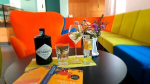 A table with a bottle of Hendrick's Gin, two glasses with drinks, a book, and a vase with flowers. - Zum Löwen-Post Hotel (Trodena)
