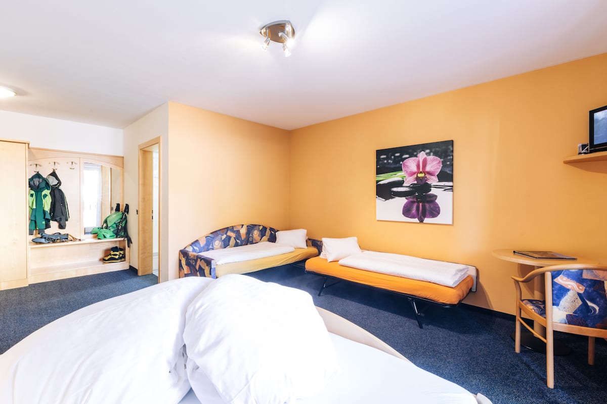 Hotellihuone, jossa on kaksi erillistä sänkyä, työpöytä, tuoli, vaatekaappi ja taulu seinällä.