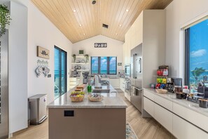 Una cocina moderna con una isla grande, electrodomésticos de acero inoxidable y vistas al océano.