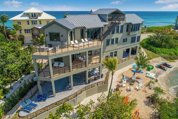 A multi-story beachfront property with balconies, outdoor seating, and a pool.