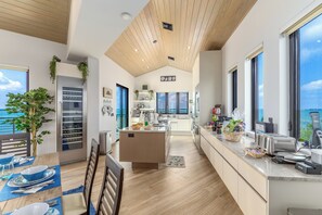 Una cocina moderna con una isla central, ventanas amplias y vista al mar.