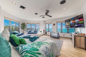 Ein geräumiges Schlafzimmer mit großem Bett, einer Sitzecke mit Meerblick und einem Fernseher, der verschiedene Streaming-Dienste anzeigt.