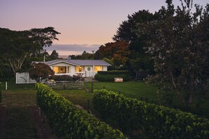 A house with a well-maintained lawn, a wooden fence, and a bench in the yard.