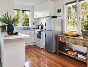 Eine moderne Küche mit weißen Schränken, einem Edelstahl-Kühlschrank und einer Holzsideboard mit Büchern.
