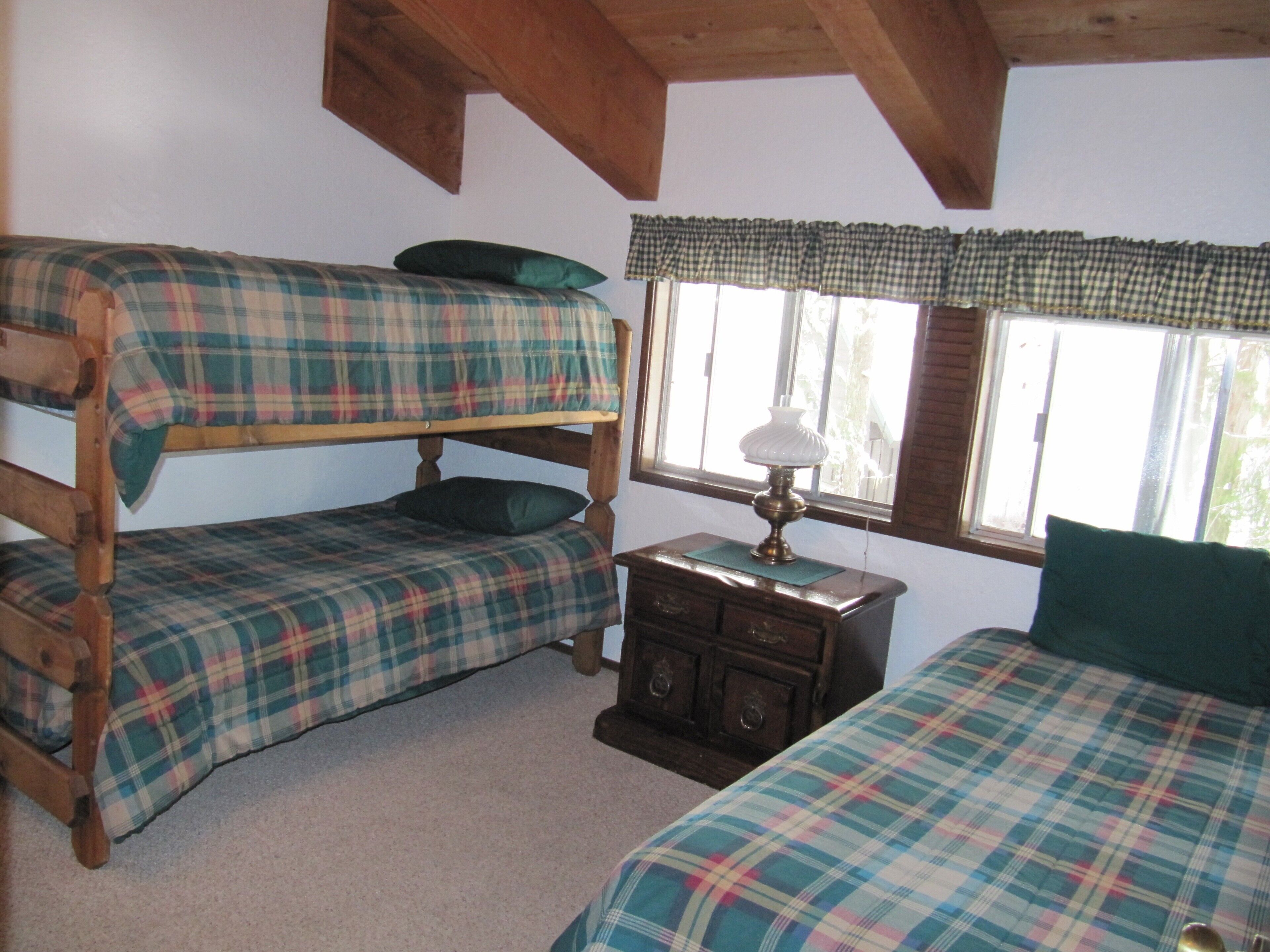 A room with two bunk beds, a wooden dresser, and a window with curtains.
