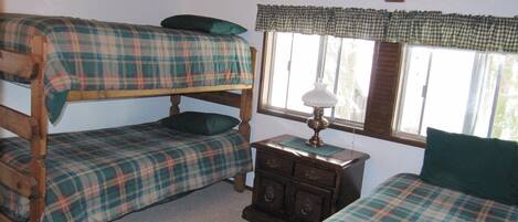 A room with two bunk beds, a wooden dresser, and a window with curtains.