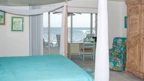 Ein Schlafzimmer mit Bett, Stuhl, Kleiderschrank und einem Balkon mit Meerblick.