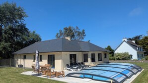 Une maison avec une piscine, du mobilier d’extérieur et une façade en pierre.