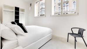 A modern bedroom with a white bed, a black chair, and a view of a building through the window. - Canal view with terrace Luxury LOFT (Venezia)