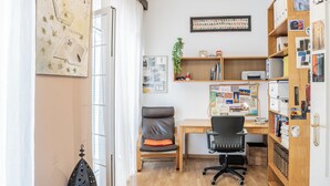 A well-lit office space with a desk, office chair, bookshelf, and a wall with various items and decorations. - Lovely apartment in the historic district of Seville (+ WiFi & AC) (Sevilla)