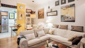 A living room with a sofa, a coffee table, and a dining area with a table and chairs. - Lovely apartment in the historic district of Seville (+ WiFi & AC) (Sevilla)