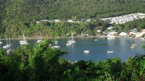 A coastal area with boats docked near a small settlement surrounded by lush green hills. - A Deshaies F5 sea view equipped for families / groups nearby beaches   (DESHAIES)