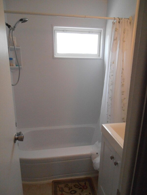 Un baño pequeño con ducha, ventana y retrete.
