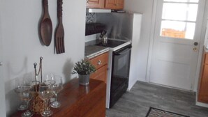 A kitchen with wooden cabinets, a stainless steel refrigerator, and a clock on the wall.