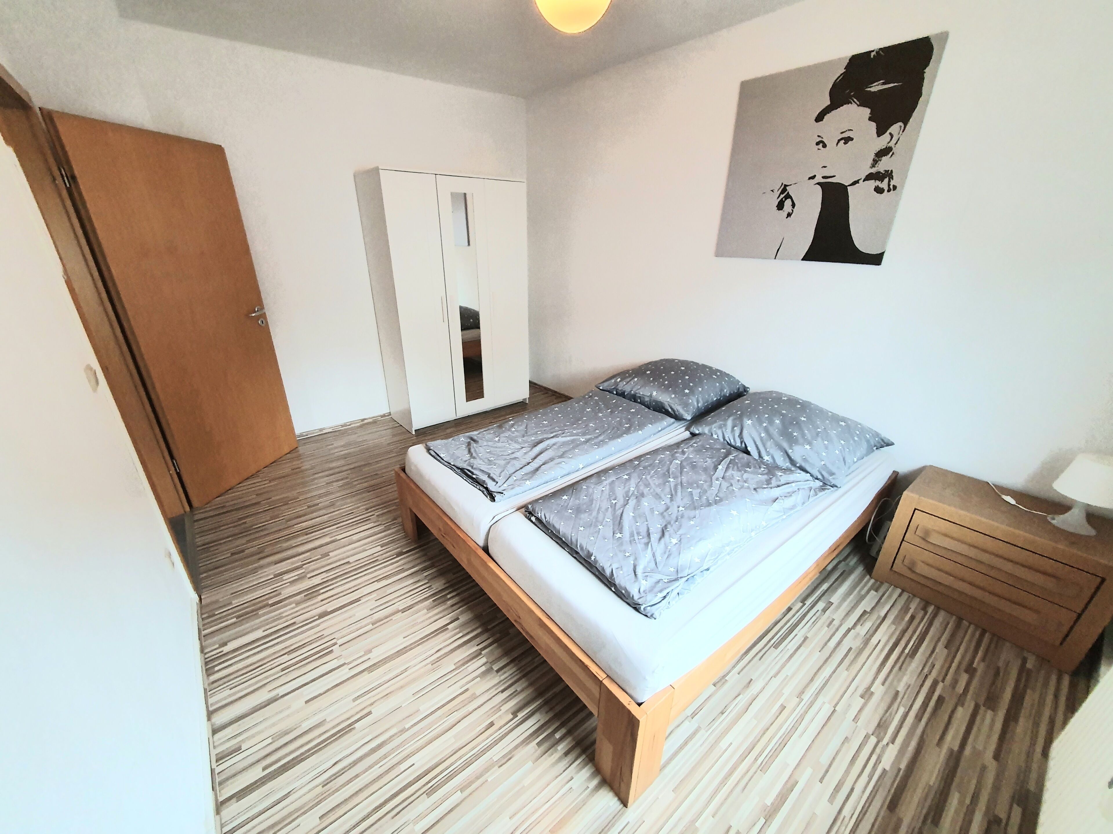 A bedroom with a bed, wardrobe, and a nightstand.