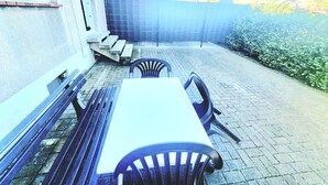 An outdoor patio with a table and chairs, a bench, and a fence.
