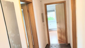 A hallway with a light fixture, a door, and a view of the outside.