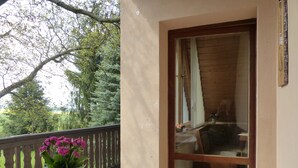 Un balcón con una mesa, una planta en maceta y vistas a una zona boscosa.