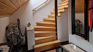 Una escalera de madera con barandilla negra, una pequeña mesa con vela y un abanico en el suelo.