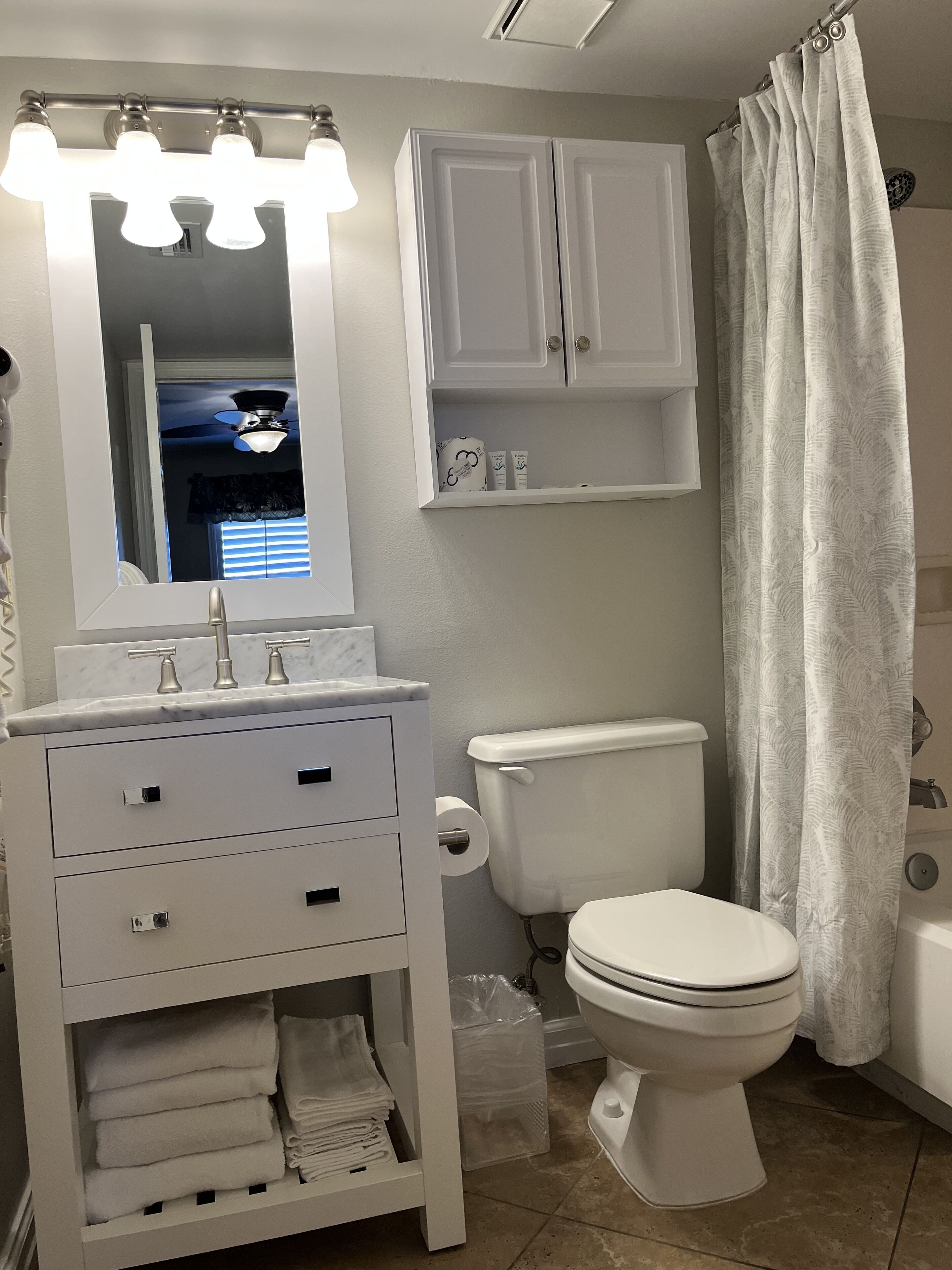Un baño con tocador blanco, inodoro y cortina de ducha.