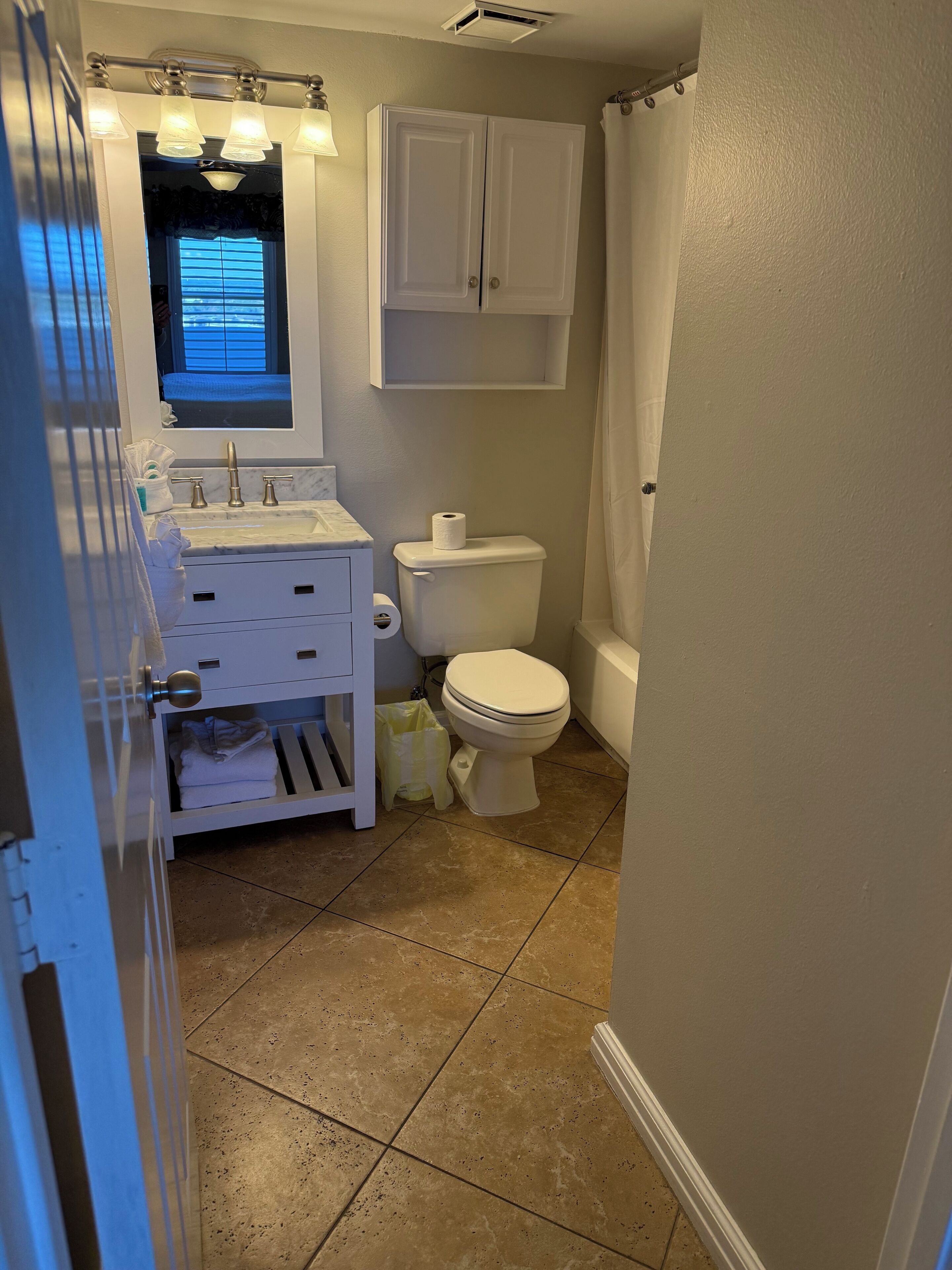 A bathroom with a toilet, sink, and cabinet.