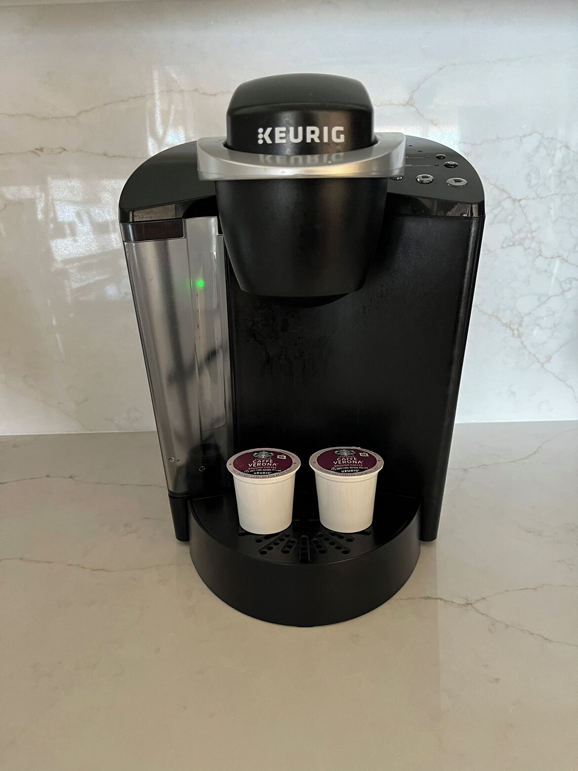 Uma cafeteira Keurig com duas cápsulas de café em sua base.