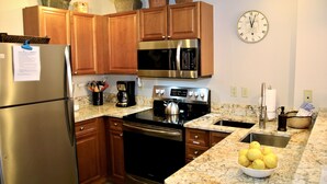 Una cocina con armarios de madera, electrodomésticos de acero inoxidable, encimera de granito y un cuenco de limones.