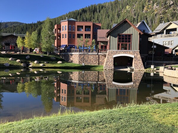 A lakeside building with a stone bridge, reflecting the surrounding trees and mountains.
