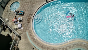 Una amplia piscina exterior con solárium, sillas de descanso y un jacuzzi más pequeño.
