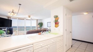 Una cocina moderna con una isla grande, un comedor con vistas y una sala de estar con ventilador de techo.