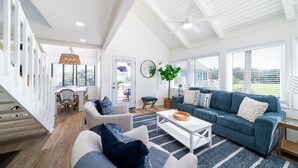 A spacious living room with a blue sofa, white coffee table, and a dining area with a table and chairs. - Bright Decor! 3 BR/3 BA Villa; Pools/Beach Nearby! Amenity access included! (Seabrook Island)