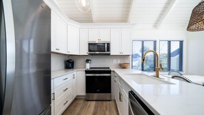 A modern kitchen with white cabinetry, stainless steel appliances, and a large island with a sink. - Bright Decor! 3 BR/3 BA Villa; Pools/Beach Nearby! Amenity access included! (Seabrook Island)
