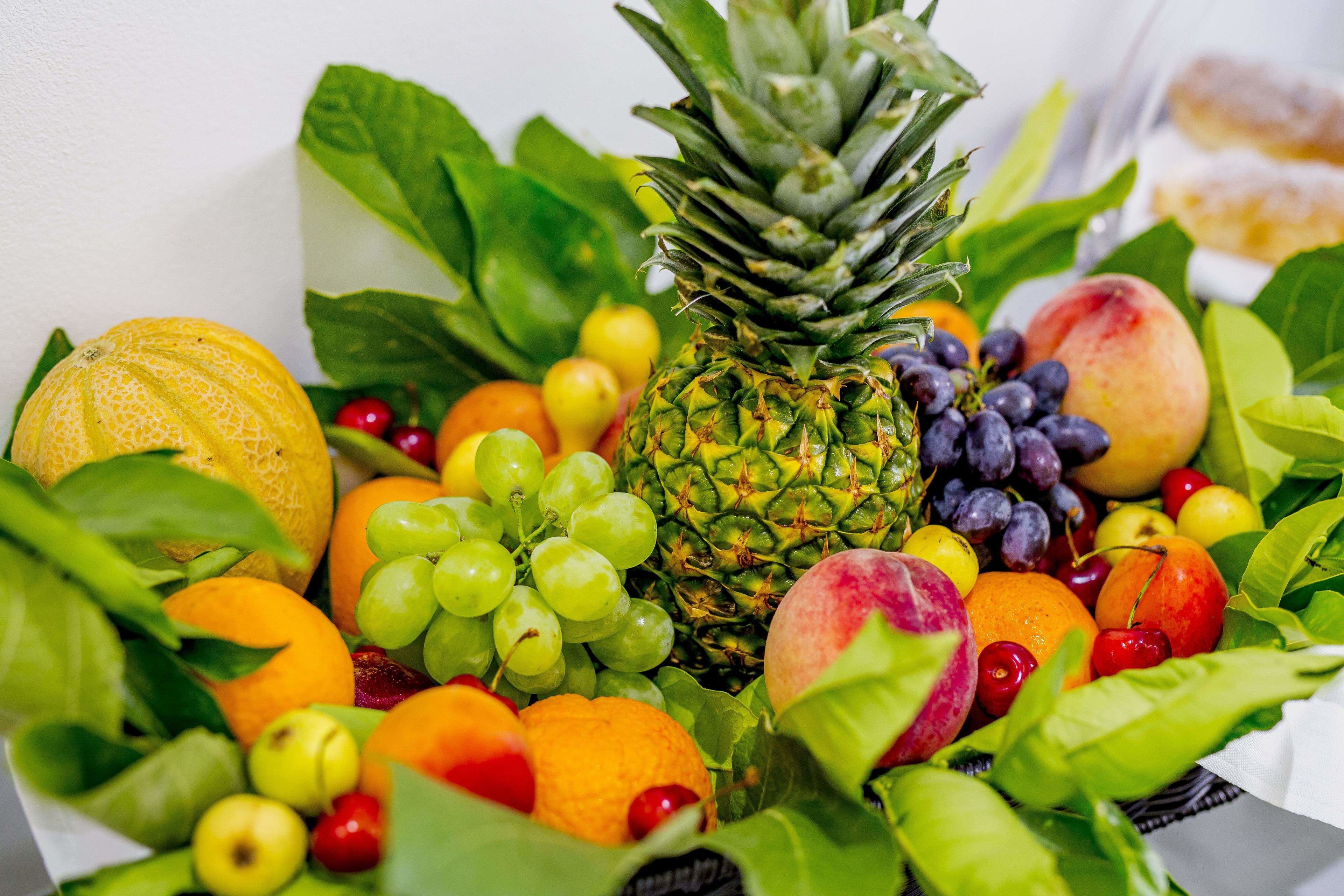 Una variedad de frutas y verduras, como piña, naranjas, uvas y melón.
