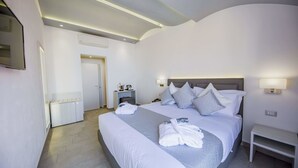 Una habitación de hotel moderna con una cama grande, lámparas de noche, una mesita de noche y una pequeña mesa.