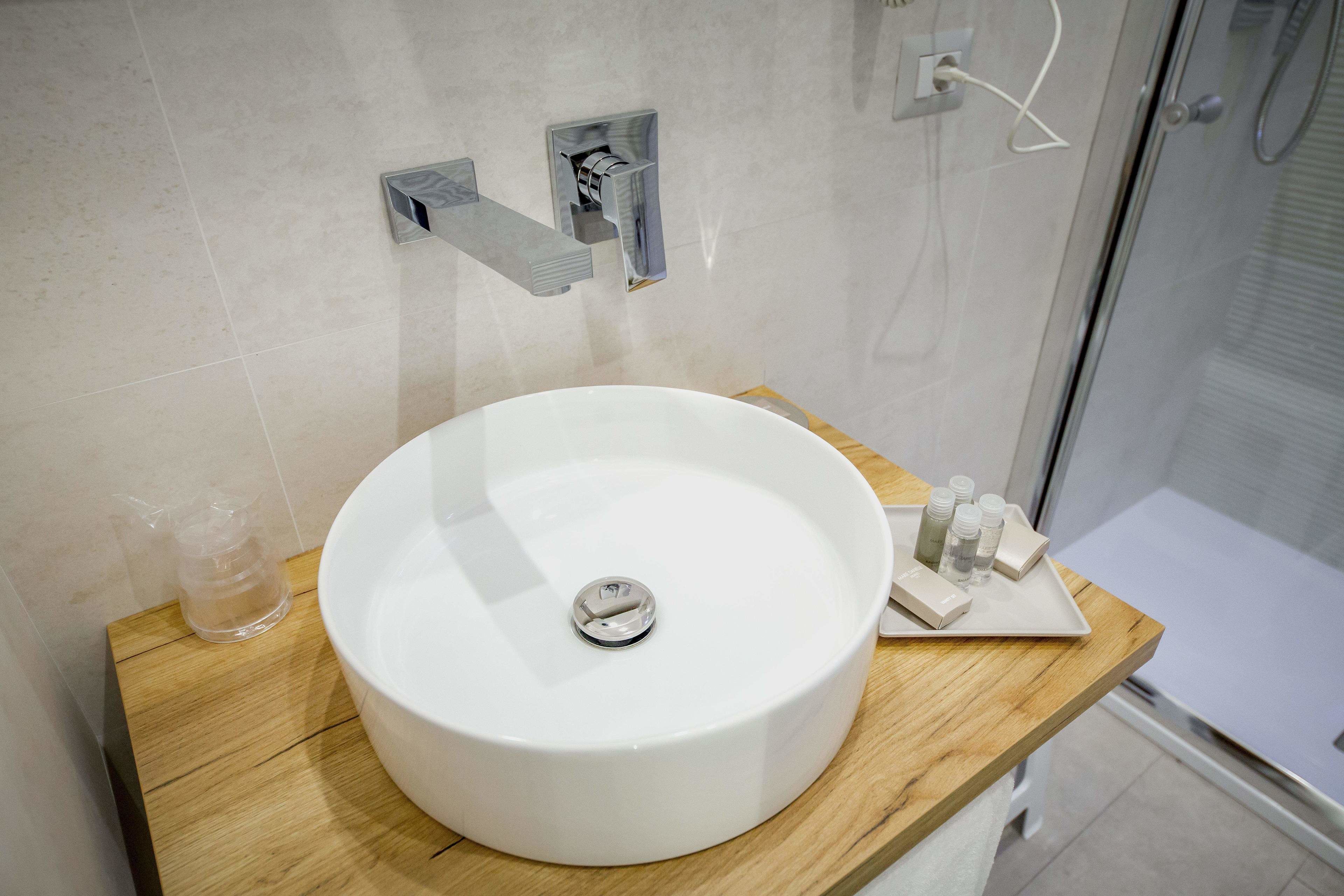 Un baño con lavamanos blanco, encimera de madera y cabina de ducha de cristal.