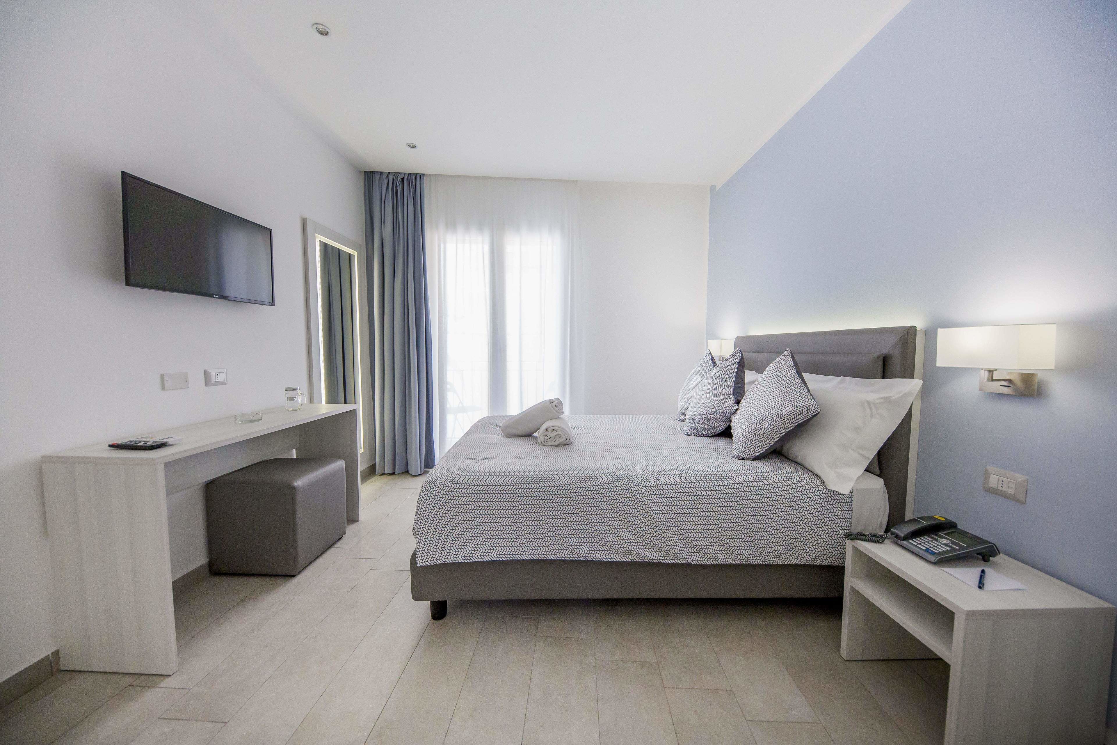 Una habitación de hotel moderna con cama, mesita de noche, televisor y un escritorio con silla.