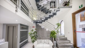 Un interior moderno con un sofá blanco, una escalera y plantas en macetas.