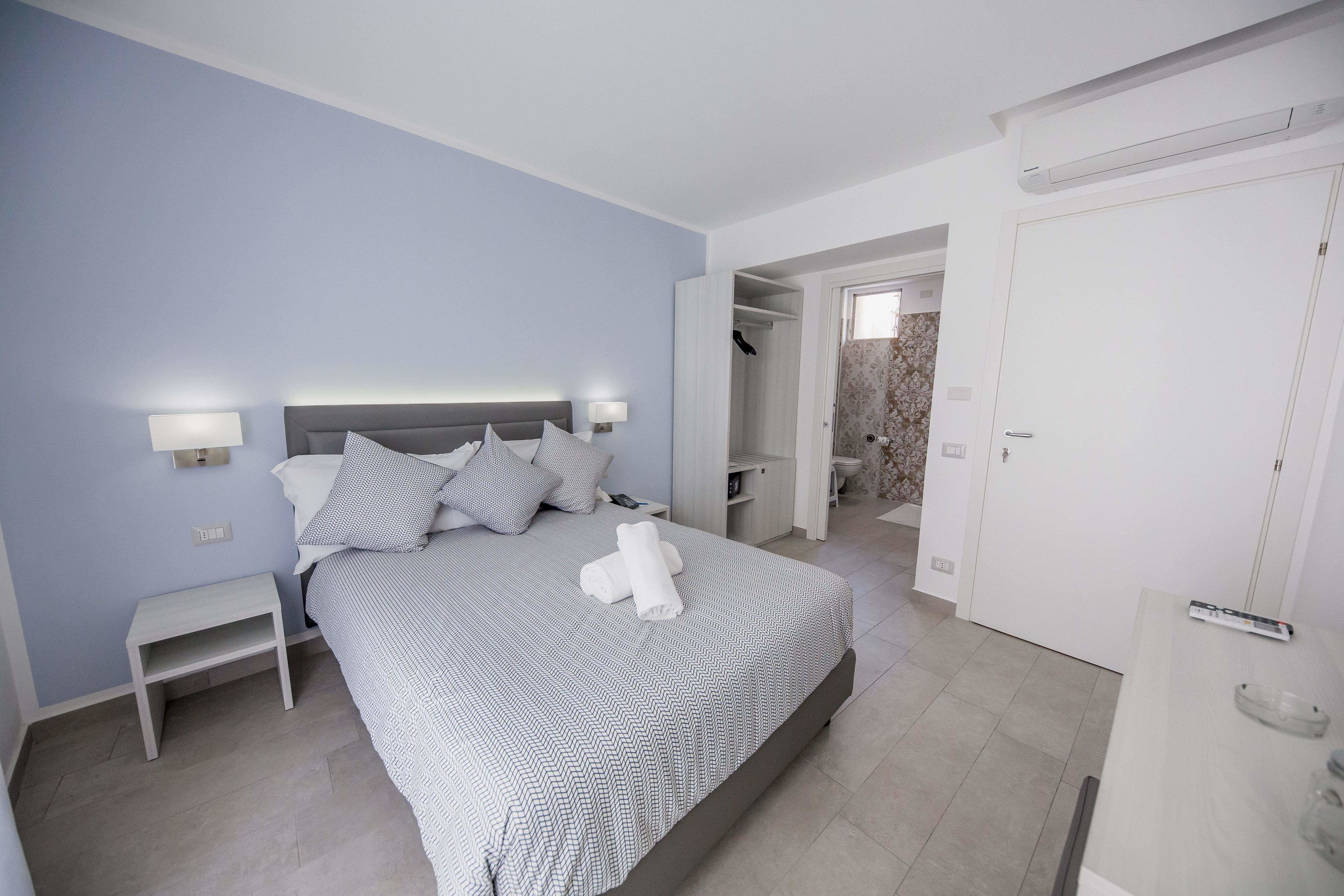 A bedroom with a bed, bedside tables, and a wardrobe.