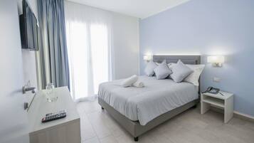 A modern hotel room with a bed, bedside table, and a desk with a remote control.
