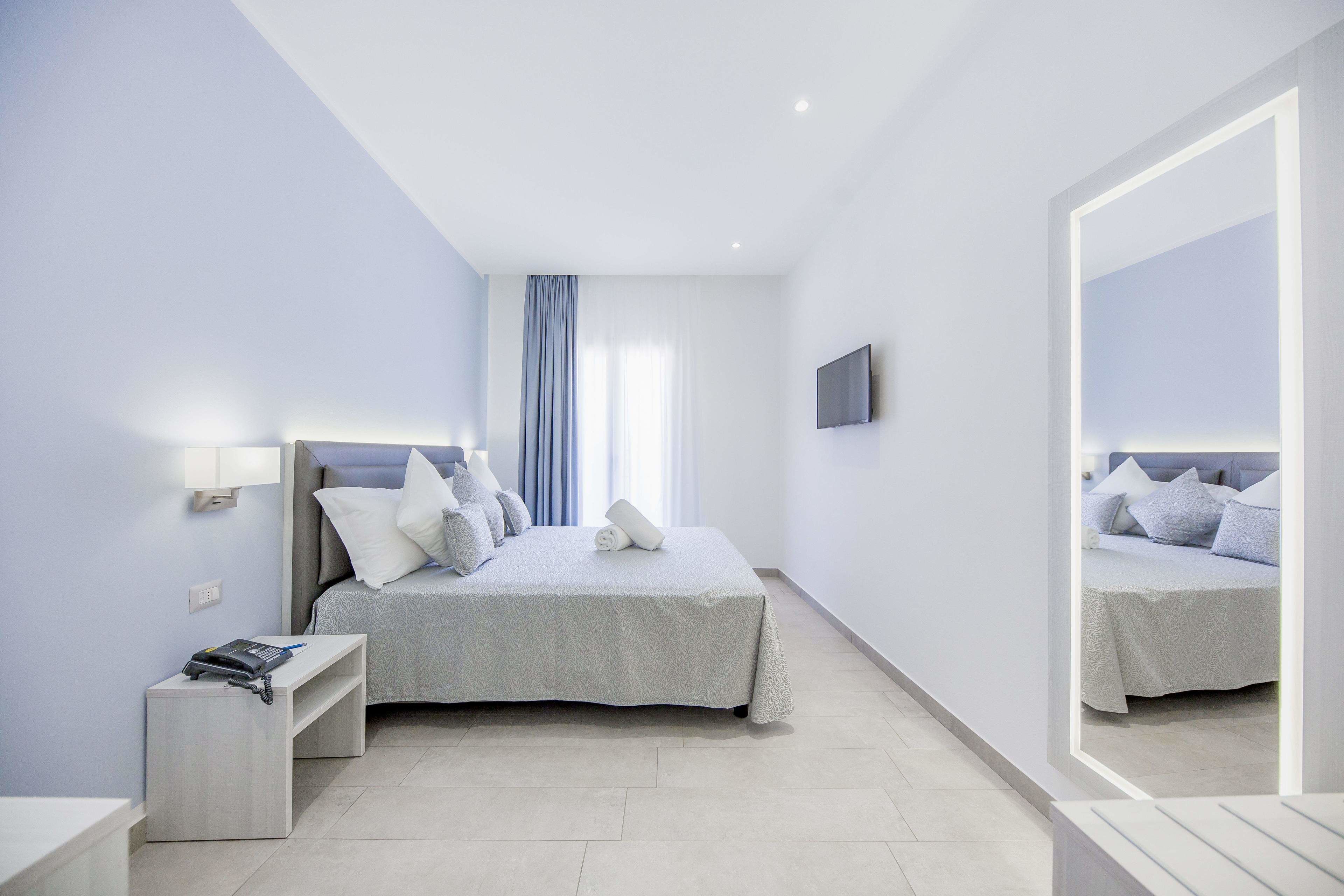 A modern bedroom with a bed, bedside table, and a mirror.