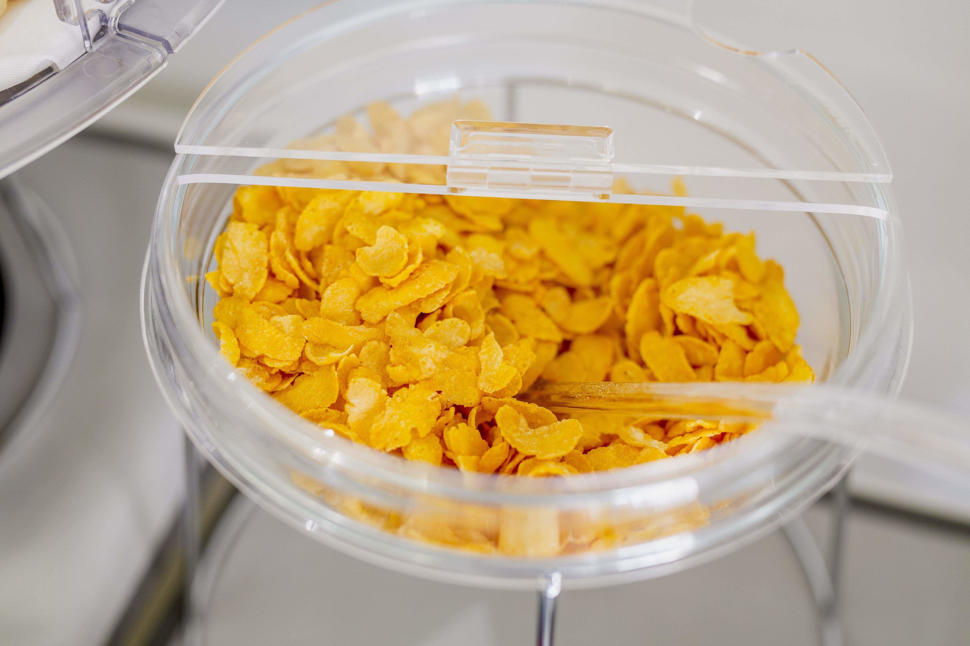 A clear plastic container filled with yellow cereal flakes.