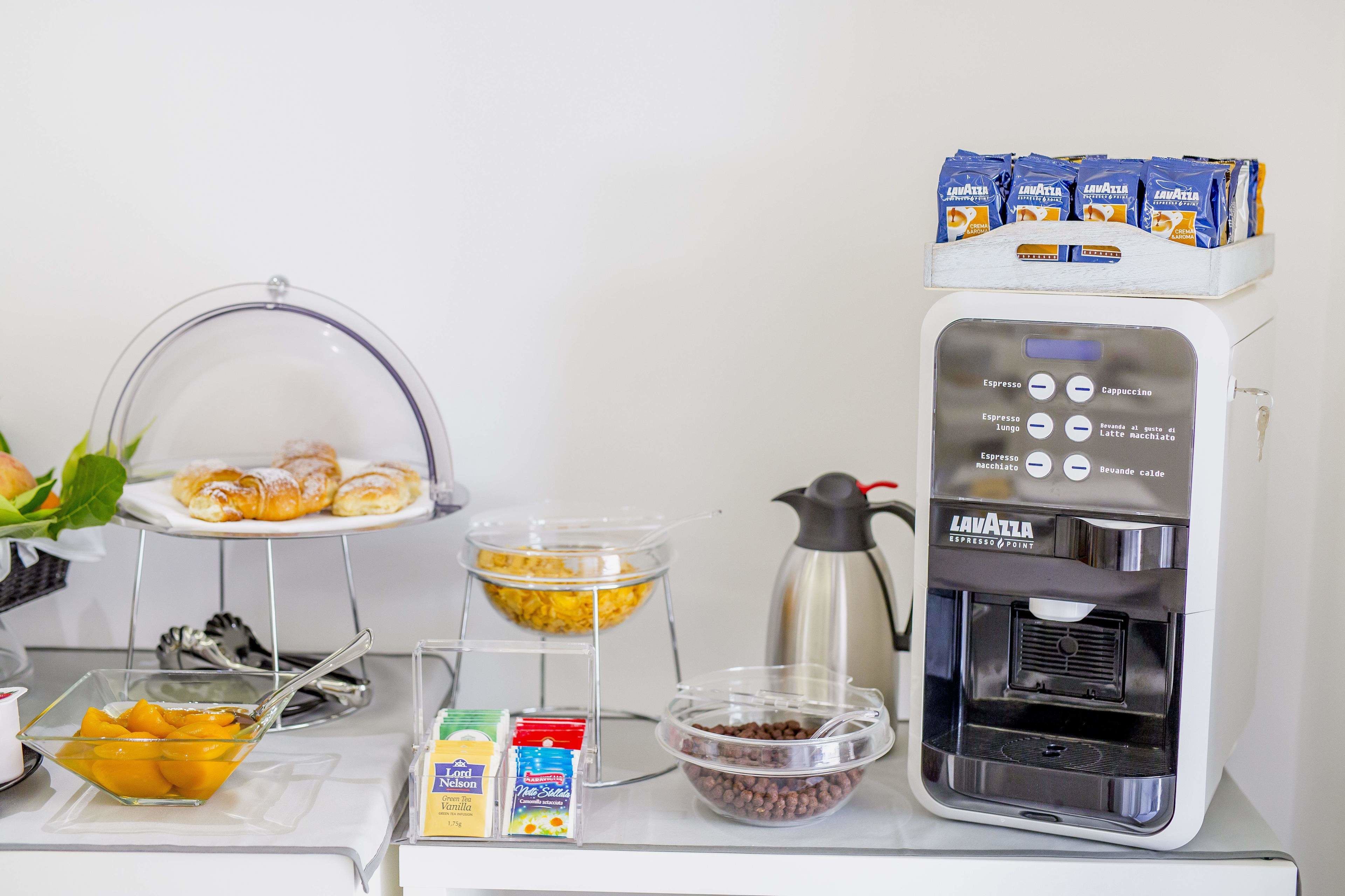 A breakfast station with a coffee machine, croissants, and various food items.