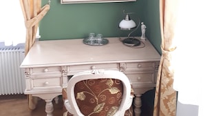 A room with a green wall, a framed portrait, a desk with a lamp, and a chair. - Pension PREMIUM (Cesky Krumlov)