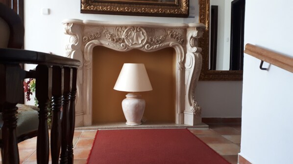 Una habitación con chimenea, alfombra roja y una lámpara.