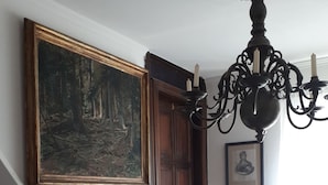 A staircase with a wooden handrail, a chandelier, a framed painting, and a statue. - Pension PREMIUM (Cesky Krumlov)