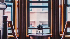 A corner room with two wooden chairs, a small table, and a stained glass window. - Northern Lights Mansion (New York)
